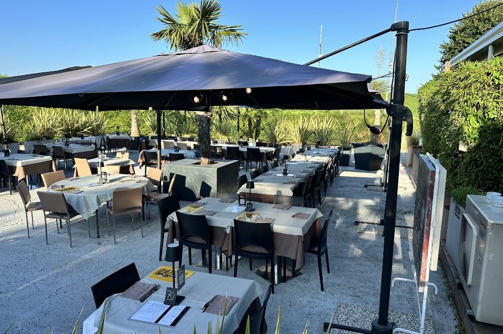 Il giardino esterno di Ermes con i tavoli apparecchiati sotto gli ombrelloni